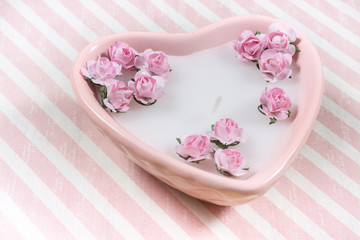 Decoration for Valentine's Day: pink heart shaped candle with little artificial flowers
