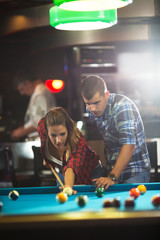 Young couple playing billiard and smiling
