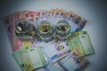 A lot coins in glass money jar on the white background Saving for house, health and travel concept.