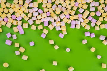 Marshmallows on green background with copyspace. Flat lay or top view. Background or texture of colorful mini marshmallows. Winter food background concept