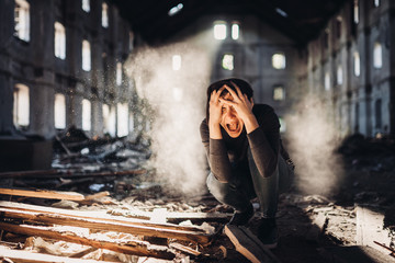 
Sad depressed person in abandoned destroyed building crying.Emotional portrait.Raped woman victim of domestic violence.Human trafficking and kidnapping.Scared and worried woman. Forced into problem.