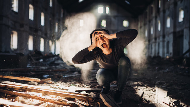 Sad depressed person in abandoned destroyed building crying.Emotional portrait.