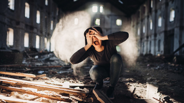 Screaming anxious person in abandoned destroyed building crying.Emotional portrait.Mentally ill woman with bipolar disorder and psychosis.Schizophrenia.Madness, crazy person.Voices in head.Tinnitus
