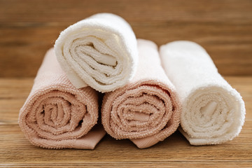 Obraz na płótnie Canvas Stack of bath towels on wooden background. White and pink cotton towels. Spa concept. Toned photo. Clean fluffy towels.