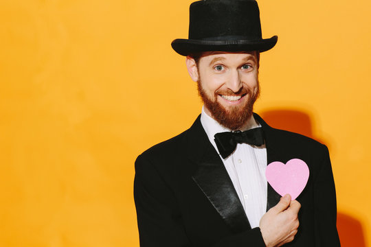 Hopeful smiling man with top hat holding a pink heart, be my valentine