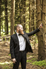businessman makes selfie on the background of pine forest.