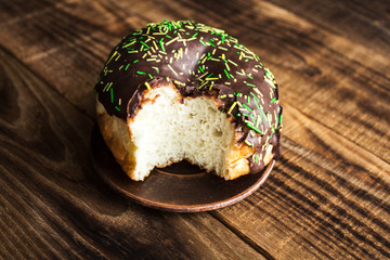 bitten donut with chocolate on a wooden background