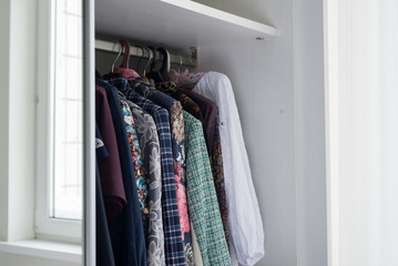 women's clothes hanging in open white cabinet