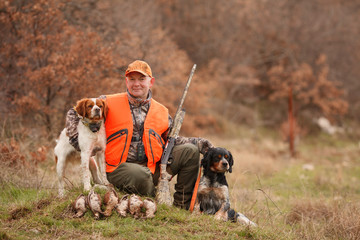 hunter with two hunting dogs, a gun and a woodcock after a hunt