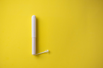 Feminine tampon with paper applicator on yellow background - obrazy, fototapety, plakaty