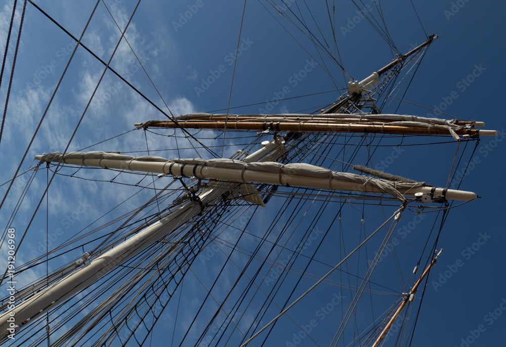 Wall mural Sailboat Mast  and ropes with cloudy blue sky in the background