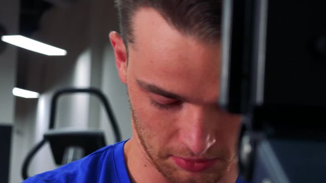 A young fit man walks on a treadmill in a gym - closeup from side