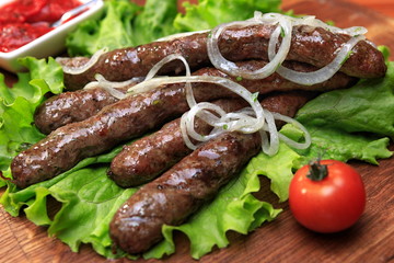 Grilled sausages on a wooden board with vegetables