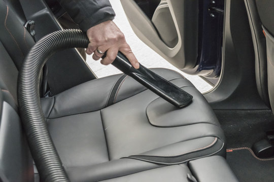 Cleaning the auto with an industrial vacuum cleaner. Car vacuum cleaner at a car wash station. Hoovering the car. Man vacuuming in the car salon. Car vacuum cleaner. 