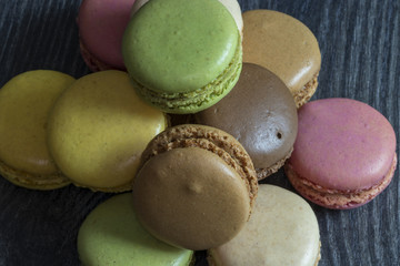 Macarons de couleurs différentes en tas sur fond noir