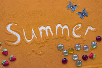 Summer inscription on an orange colored sand with decorations, top view, flat lay