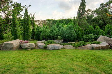 Stone park & bush are blue sky day. This have grass in foreground.