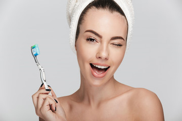 winking young woman with tooth brush isolated on white
