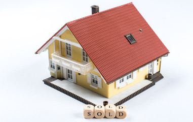 Model house with word Sold on wooden cube