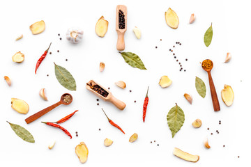 Seasoning background. Dry spices near ginger, garlic, chili, laurel leaf on white background top view pattern