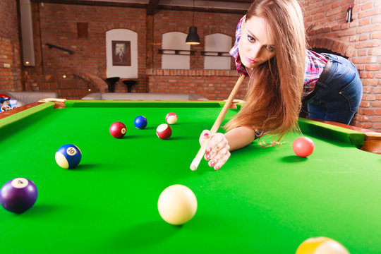 Young woman playing billiard.