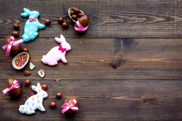 Easter composition. Easter sweet gift. Chocolate eggs near cookies in shape of Easter bunny on dark wooden background top view space for text
