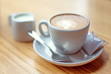 White cup of coffee with milk and sugar on the wooden table 