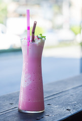 Pink milk smootie serve in high glass on steel table and wood table