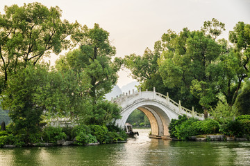 Scenic marble bridge on lake among trees at sunset, Guilin © efired