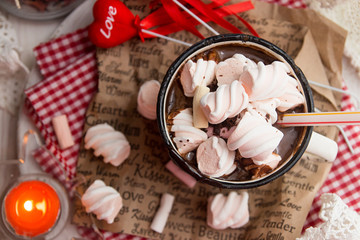 Mug of hot chocolate drink with marshmallow candies on top and candles on white background. Valentin's day love concept.