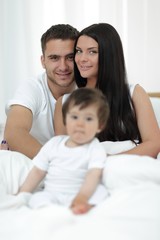 Cute little boy with parents on the bed