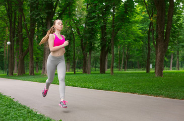 Young woman running in green park, copy space