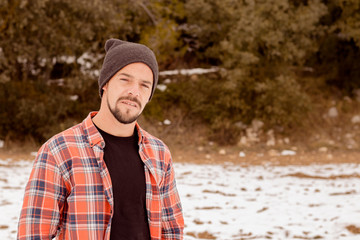 Pensive man with beard,plaid t-shirt,hat and casual clothes. A young and carefree lifestyle.
