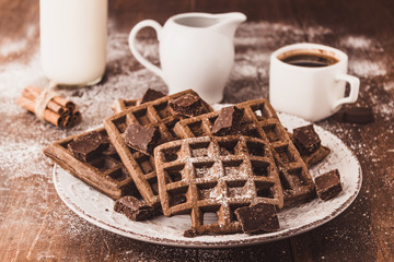 Vienna Belgian chocolate waffles on a plate dusted with powdered sugar a Cup of coffee milkman and cinnamon sticks Delicious pastries close-up