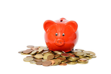 Rotes Sparschwein steht auf einem Haufen von Münzen vor weißem Hintergrund