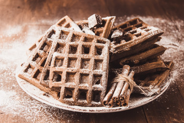 Vienna Belgian chocolate waffles on a plate dusted with powdered sugar and cinnamon sticks Delicious pastries