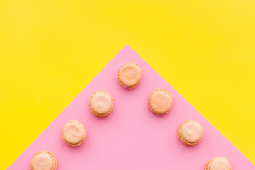 Macarons dessert. Pattern on yellow and pink pastel background top view copy space