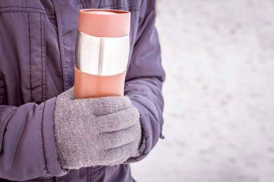 thermos in the hands of a man close-up against the snow
