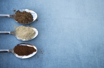 Variety of spices including chilli powder and curry powder on silver spoons 