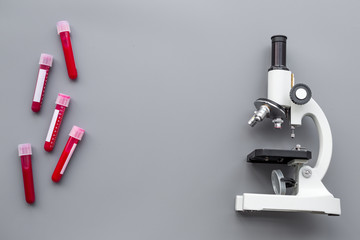 Do blood test in laboratory. Analysis. Blood samples in test tubes near microscope on grey background top view copy space