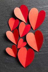 Obraz premium Red handmade paper hearts on a slate background