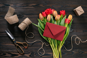 flat lay with bouquet of tulips, envelope and decoration supplies on wooden tabletop © LIGHTFIELD STUDIOS