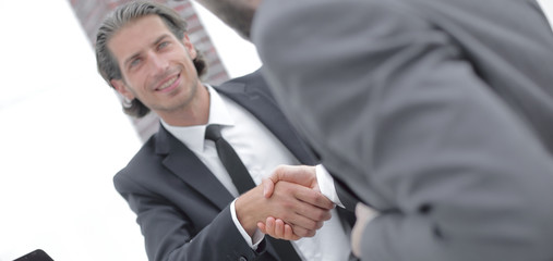 handshake business partners in front of the open laptop