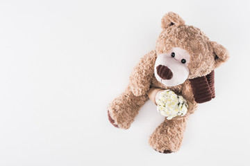 top view of teddy bear with bouquet of white flowers isolated on white