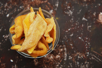 Dehydrated Healthy Mango Slices in Glass Bowl over Rusty Vintage Background.