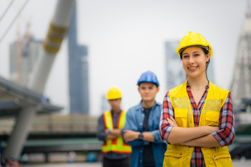Portrait of young engineer girl, posing outdoor with team and construction on background
