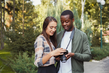 Multiethnic couple watching pictures on camera