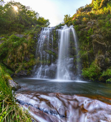 Fototapeta na wymiar Water flows over the rocks under a waterfall