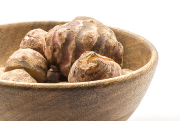 Jerusalem artichoke closeup in a wooden bowl isolated on white background sweet crisp topinambur.