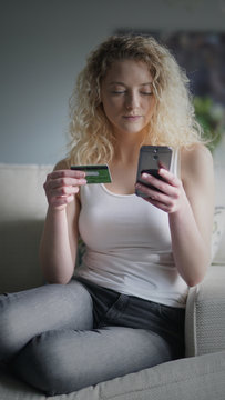Attractive blonde woman sits on a couch while shopping online